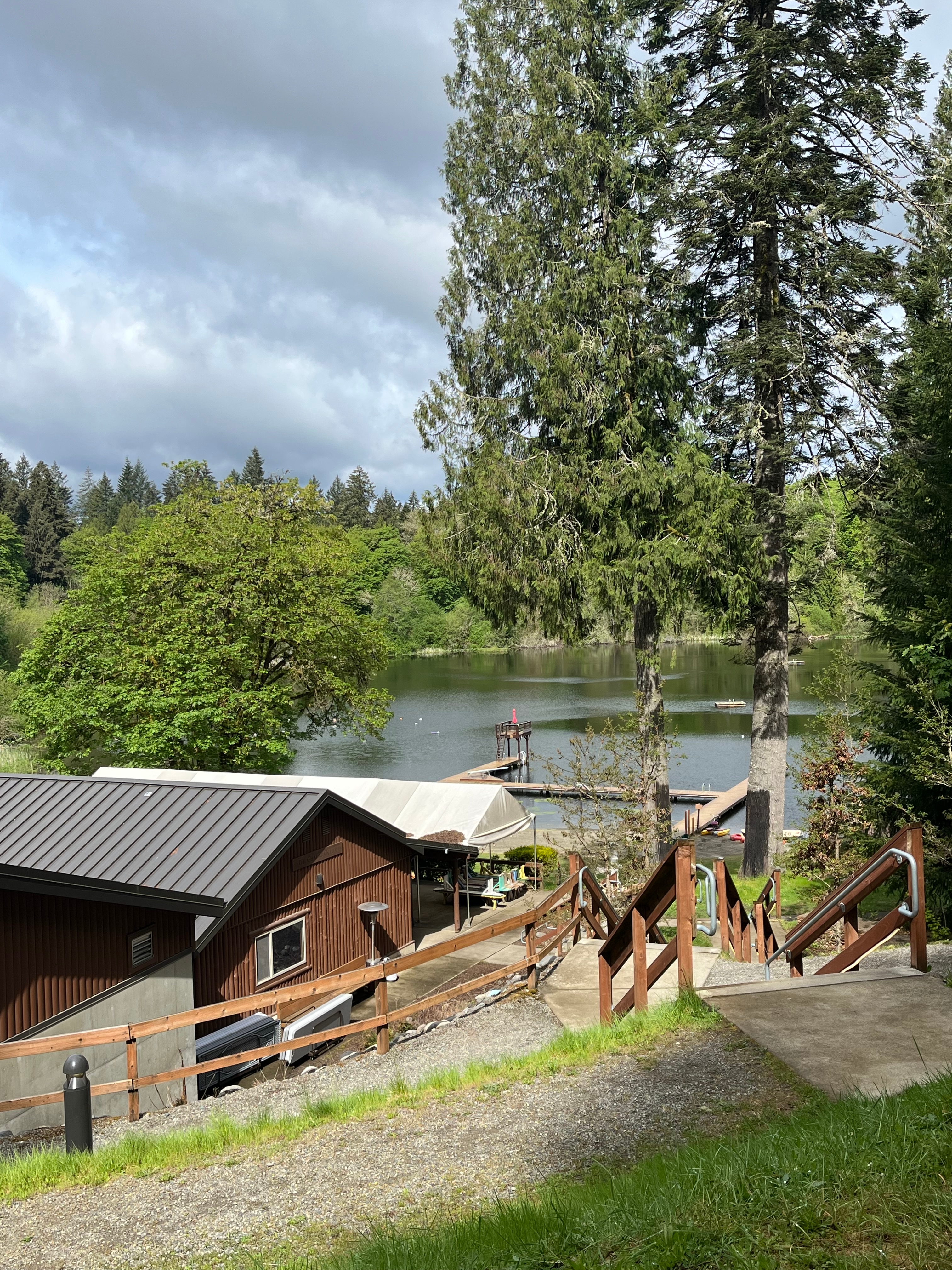 WOSLN lake cabins In a wooded area, concrete stairs and wooden railings lead to cabins along a lake with a swimming dock and diving board