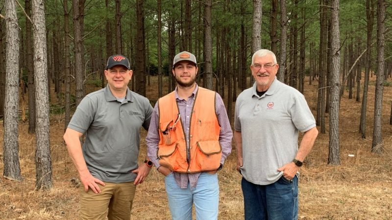 Josh Turner, Caleb Turner, and Dale Turner stand together in front of pine trees
